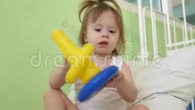 小宝宝正坐在医院病房的床上玩玩具.. 生病的女孩在医院里康复